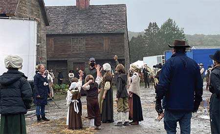 Director Anne Fletcher directing cast in a 1600s New England village set